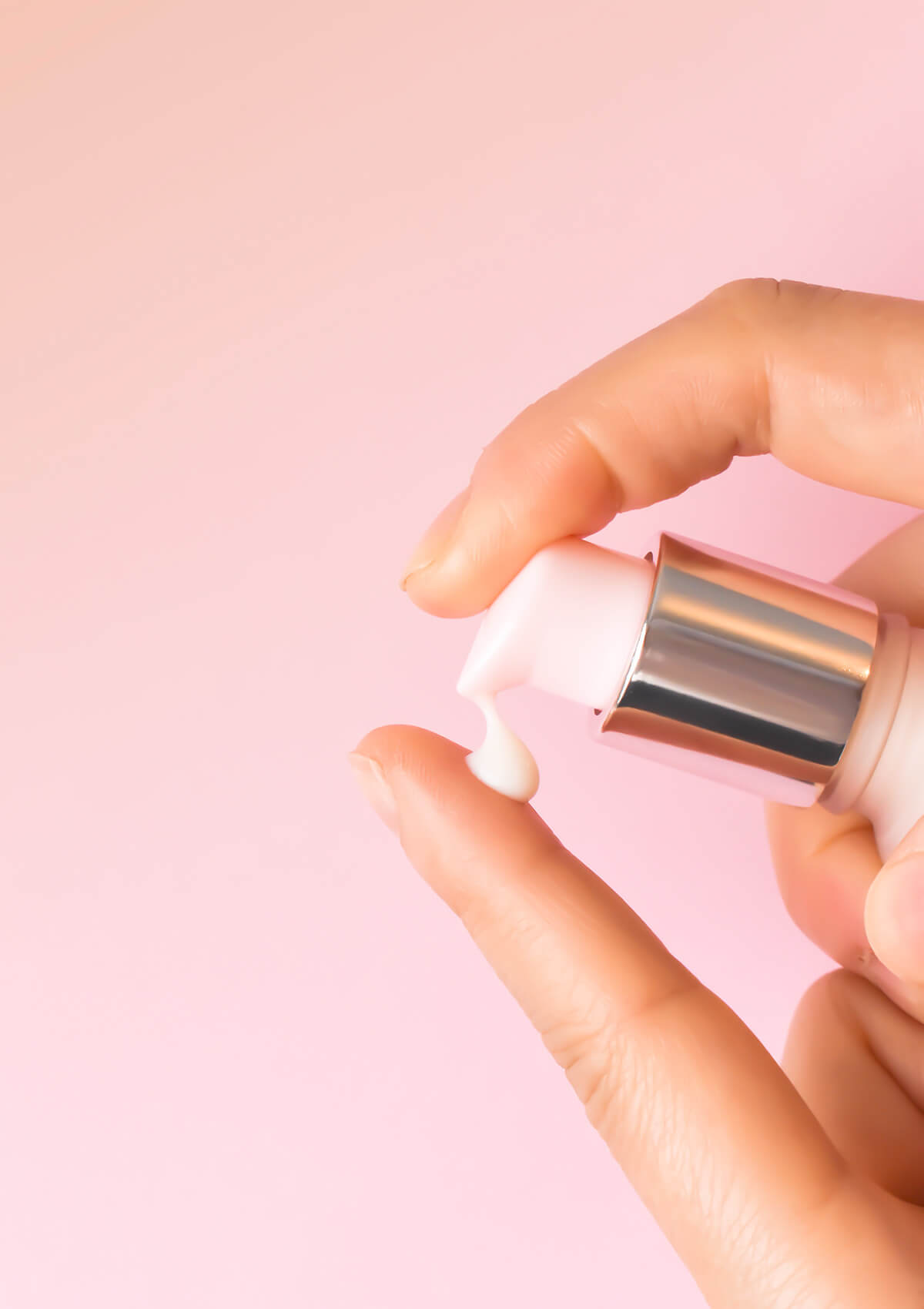 Ein Finger pumpt einen Klecks Active Brightening Serum auf einen Finger. Rosafarbener Hintergrund