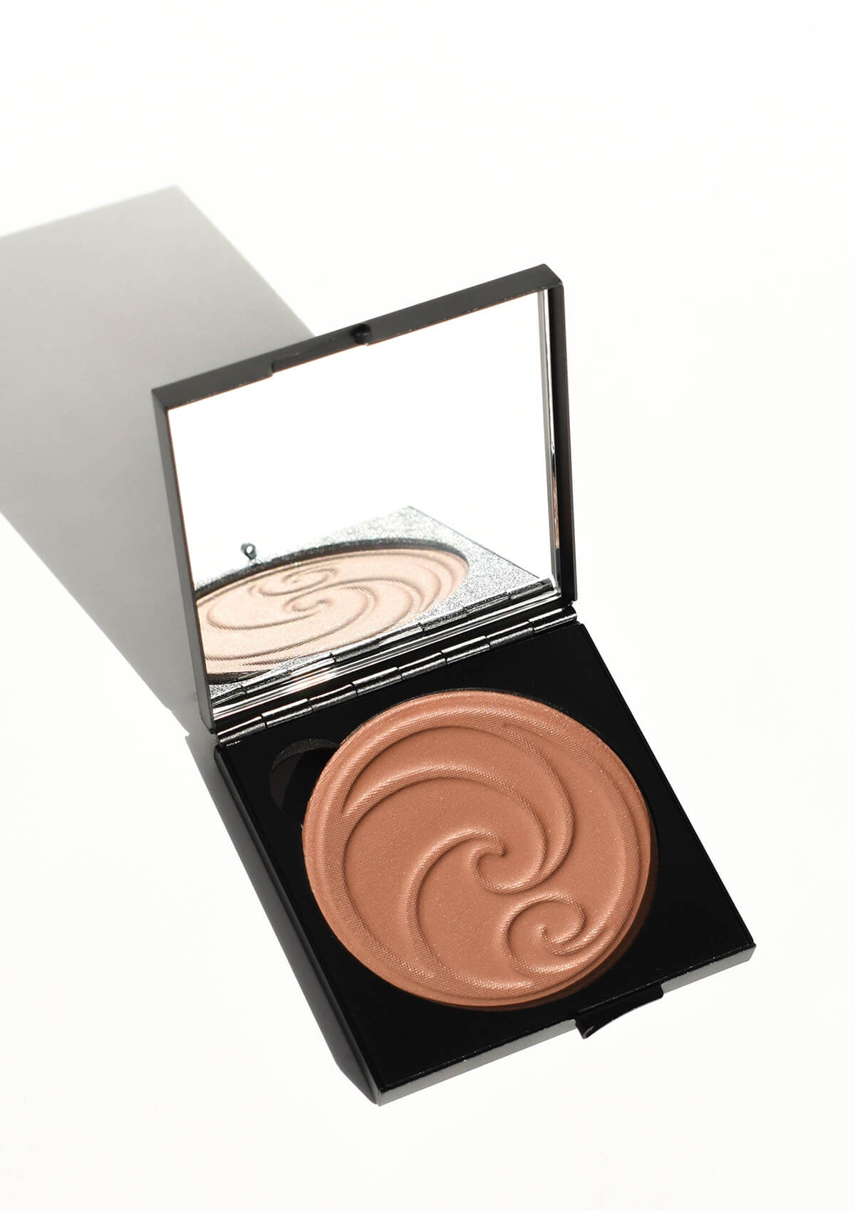Geöffnete Puderschatulle mit Spiegel und braunem Puder als Kringel von Living Nature