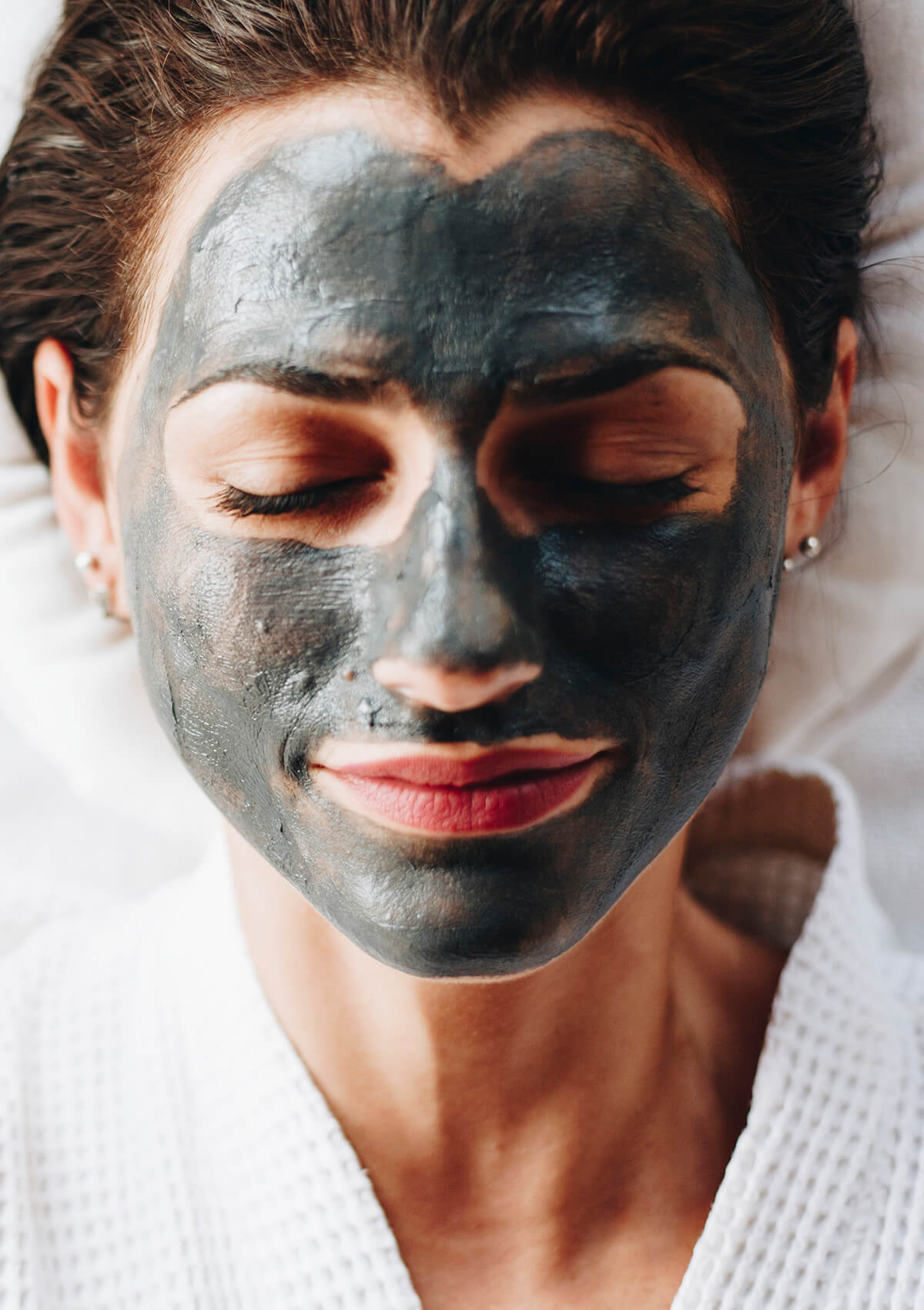 Schlafende Frau mit Charcoal Clay Mask im Gesicht