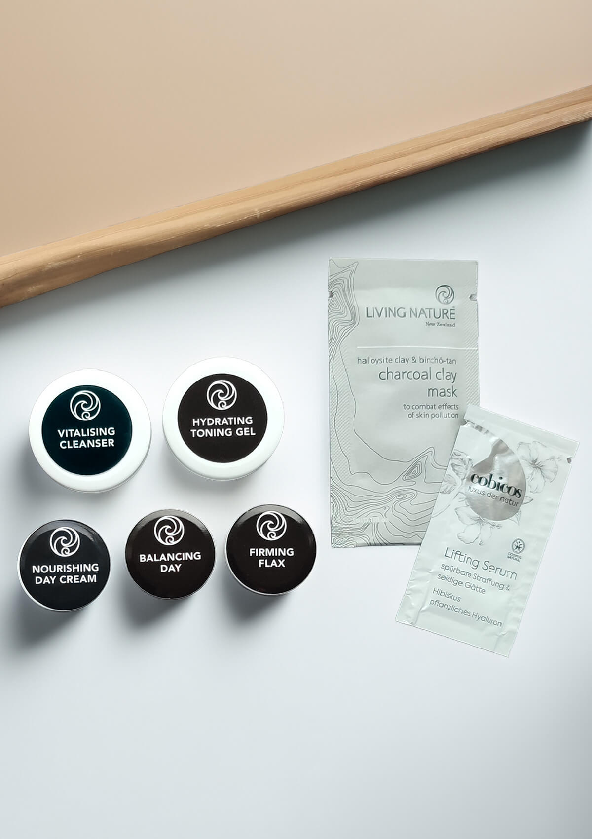 Fünf kleine Dosen mit schwarzem Etikett von: Hydrating Toning Gel, Vitalising Cleanser, Balancing Day, Nourishing Day Cream und Firming Flax Serum. Und ein Sachet Lifting Serum und Charcoal Clay Mask.