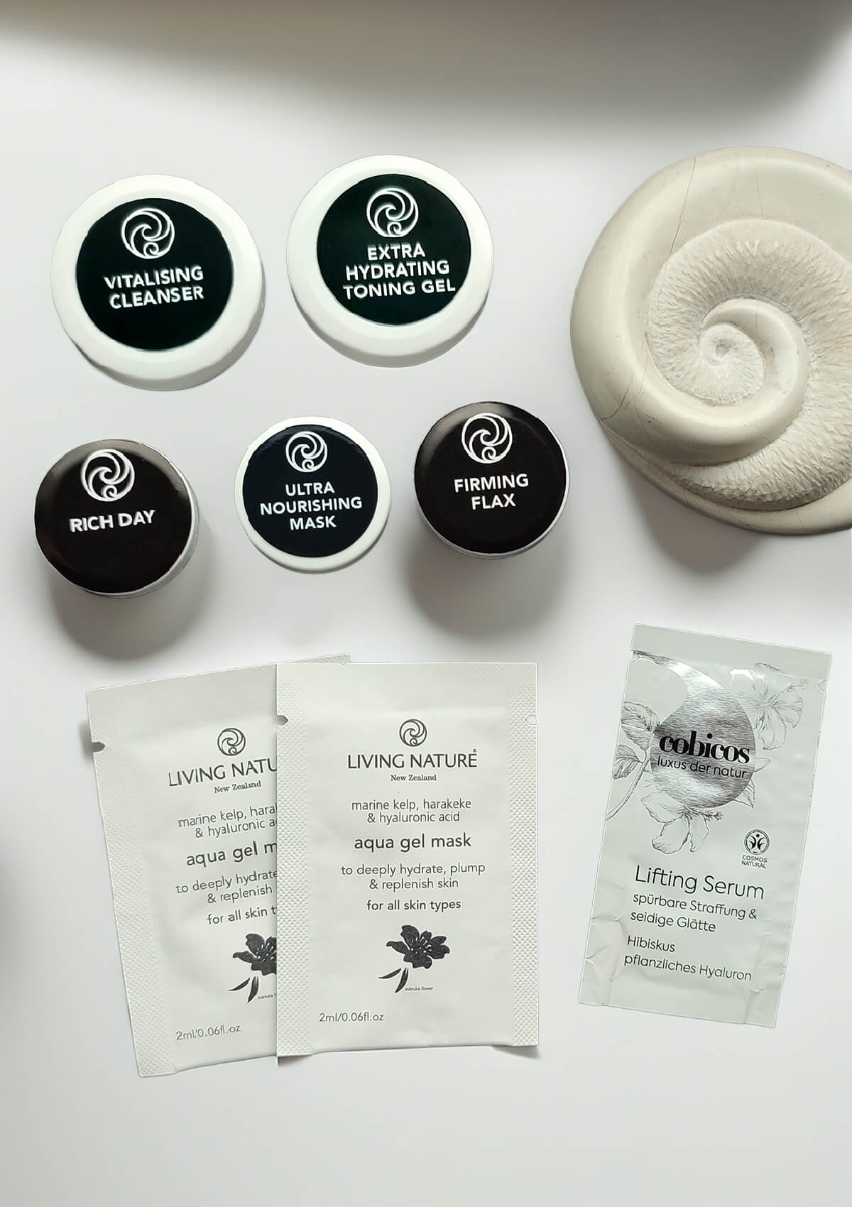 Fünf kleine Dosen mit schwarzem Etikett von: Extra Hydrating Toning Gel, Vitalising Cleanser, Rich Day, Ultra Nourishing Mask und Firming Flax Serum. Und ein Sachet Lifting Serum und zwei Sachets Aqua Gel Mask.