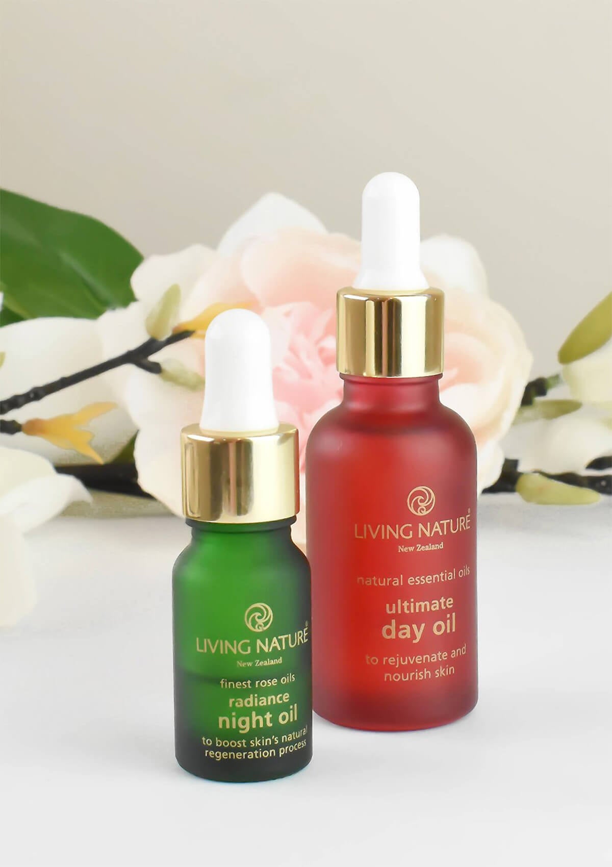 Ultimate Day Oil in einer roten Glasflasche mit weißer Pipette neben dem Radiance Night Oil in einer kleineren grünen Glasflasche mit einer weißen Pipette