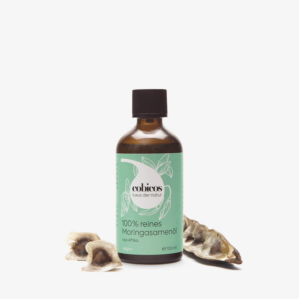 cobicos 100 Prozent reines Moringasamenöl aus Afrika. Für Veganer geeignet. 100 ml Glasflasche mit Kinder-Sicherheits-Schraubverschluss. Daneben Moringasamenschote