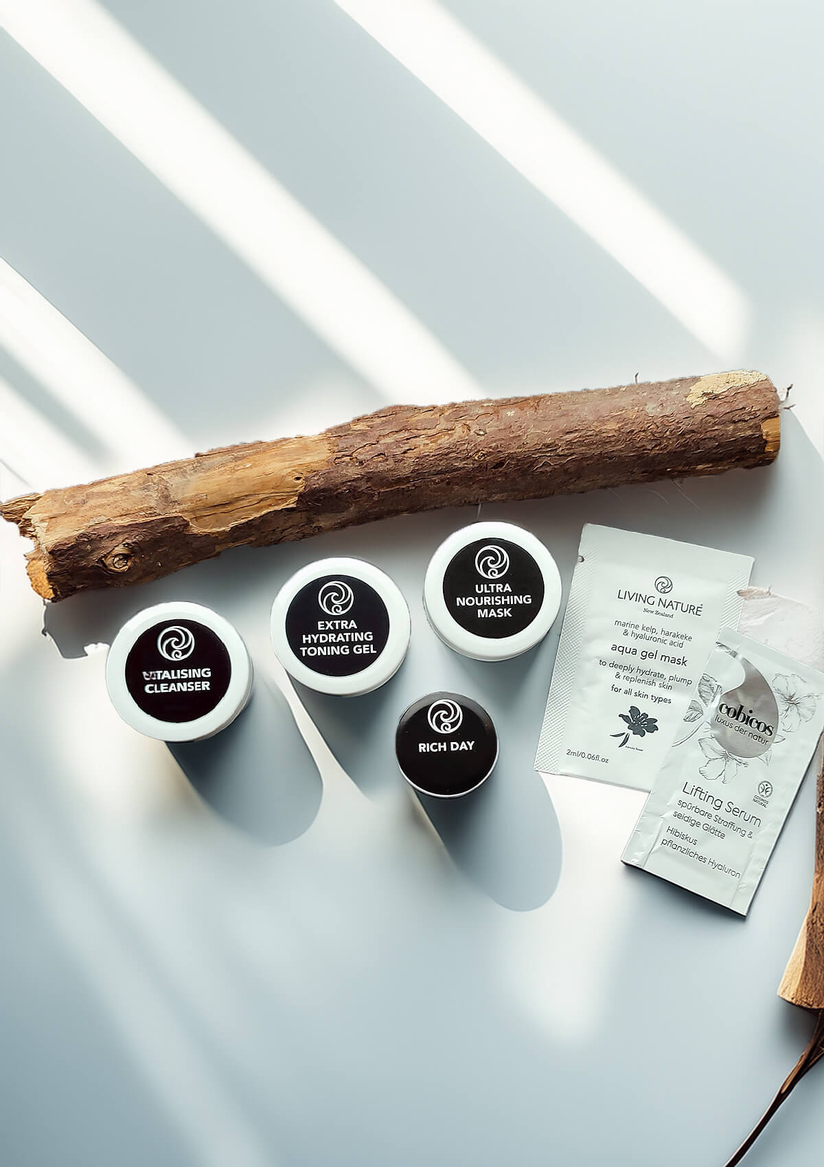 Vier kleine Dosen mit schwarzem Etikett von: Extra Hydrating Toning Gel, Vitalising Cleanser, Rich Day, Ultra Nourishing Mask. Und ein Sachet Lifting Serum und Aqua Gel Mask.