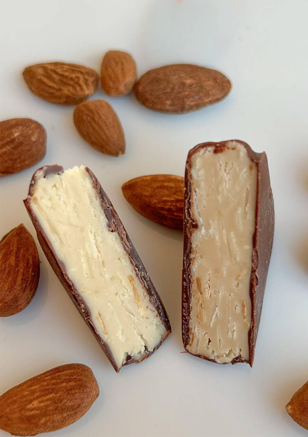 Bio-Mandelnougatstück, aufgeschnitten, helle Füllung mit dunklem Schokoladenüberzug und Mandeln